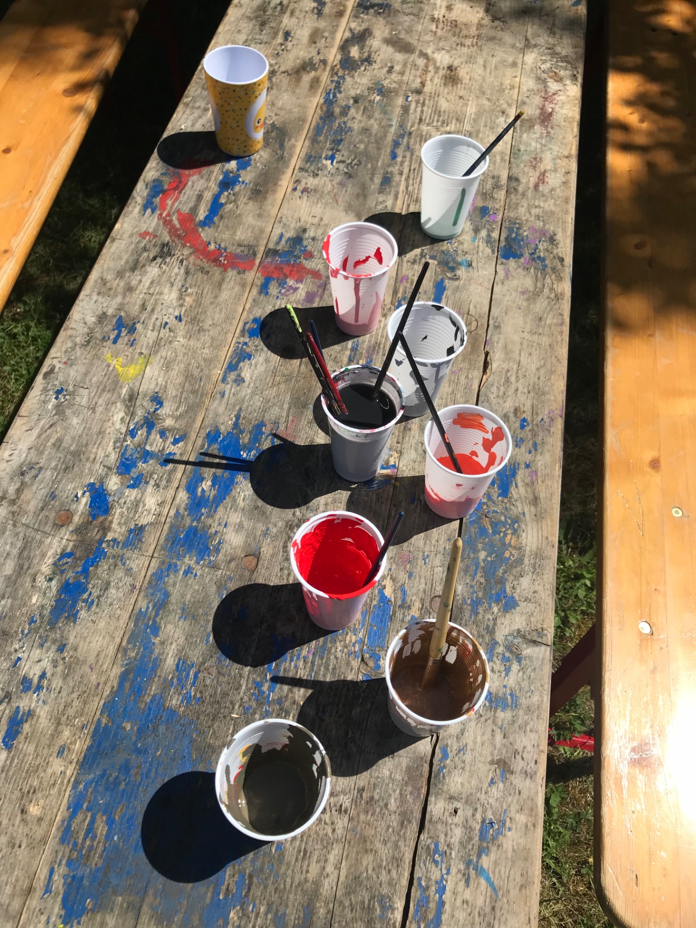 Bunte Wasserfarben in Bechern auf einem Basteltisch